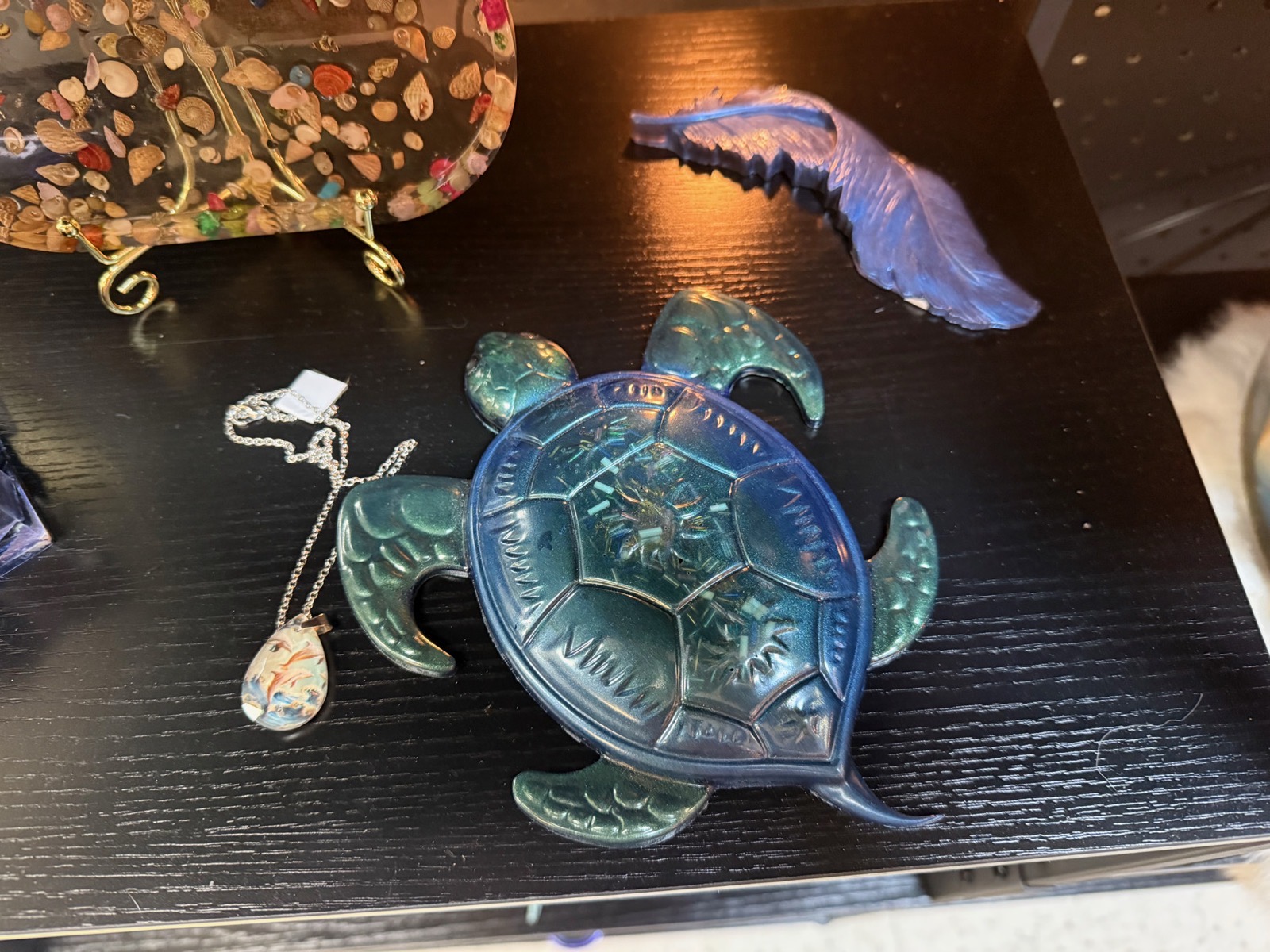Blue-green iridescent resin sea turtle dish beside a coastal pendant necklace