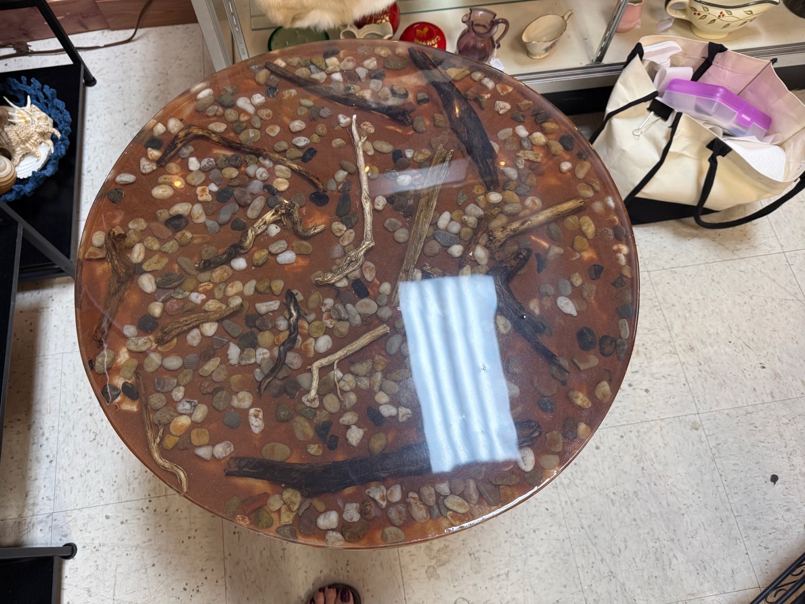 Round resin tabletop filled with river stones and driftwood branches